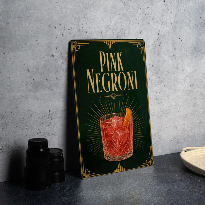 A framed poster advertising "PINK NEGRONI" cocktail, featuring an illustration of a glass filled with the drink and garnished with an orange slice.