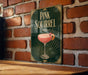 A sign for a pink squirrel cocktail is displayed on a brick wall.