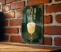 A sign for a drink called "Pisco Sour" is displayed on a brick wall.