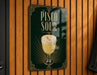 A sign for a drink called "Pisco Sour" is displayed on a wooden wall.