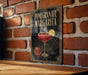 A decorative sign for a pomegranate margarita cocktail, featuring a glass of the drink and garnished with a lemon slice.