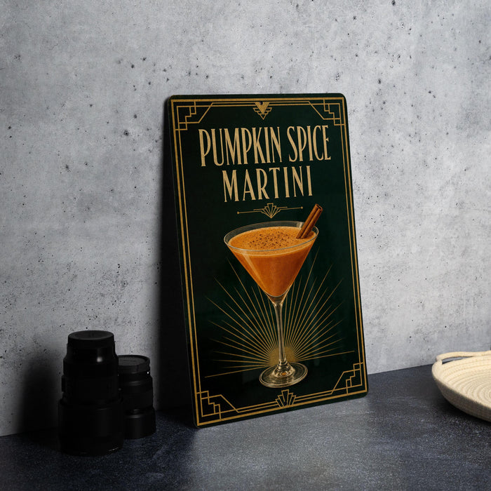 A framed image of a pumpkin spice martini on a wall, with a stack of black containers and a white dish visible to the side.