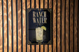 A sign for Ranch Water is displayed on a wooden wall.