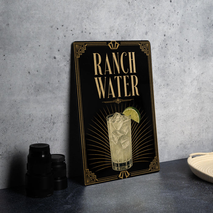 A sign for "Ranch Water" featuring an illustration of a drink with a lime slice, placed on a countertop next to some black containers.