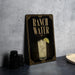 A sign for "Ranch Water" featuring an illustration of a drink with a lime slice, placed on a countertop next to some black containers.