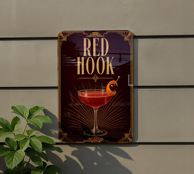 A sign for "Red Hook" cocktail, featuring a glass of red cocktail with a cherry on top, is displayed on a wall.