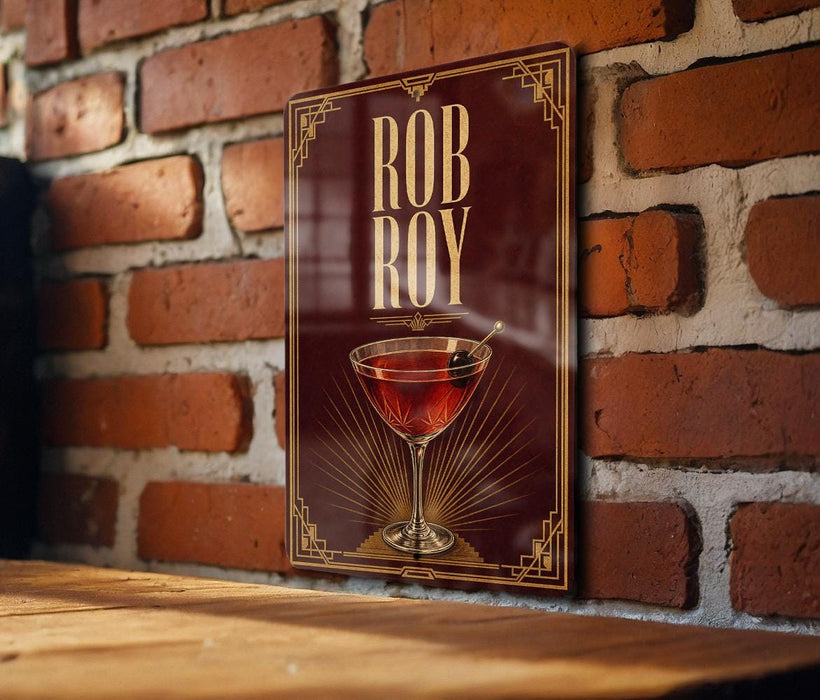 A framed poster of a martini glass with the name "ROB ROY" displayed on it, mounted on a brick wall.