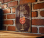 A sign with the text "ROSÉ SANGRIA" and an illustration of a glass of rose-colored wine against a brick wall background.
