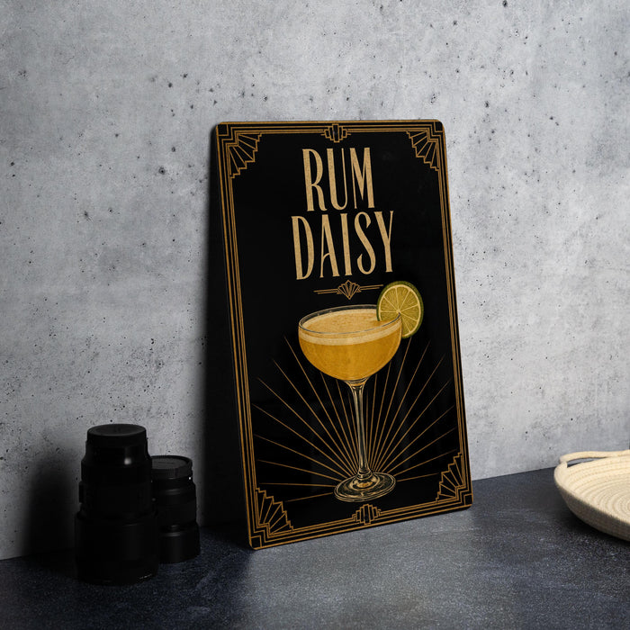 a framed illustration of a cocktail glass with a lemon slice, accompanied by the text "RUM DAISY" on a black background with an Art Deco style design.