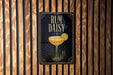 A poster with the text "RUM DAISY" and an illustration of a cocktail glass with a lemon slice.