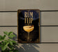a sign with the text "RUM FLIP" and an illustration of a cocktail glass with a cinnamon stick.