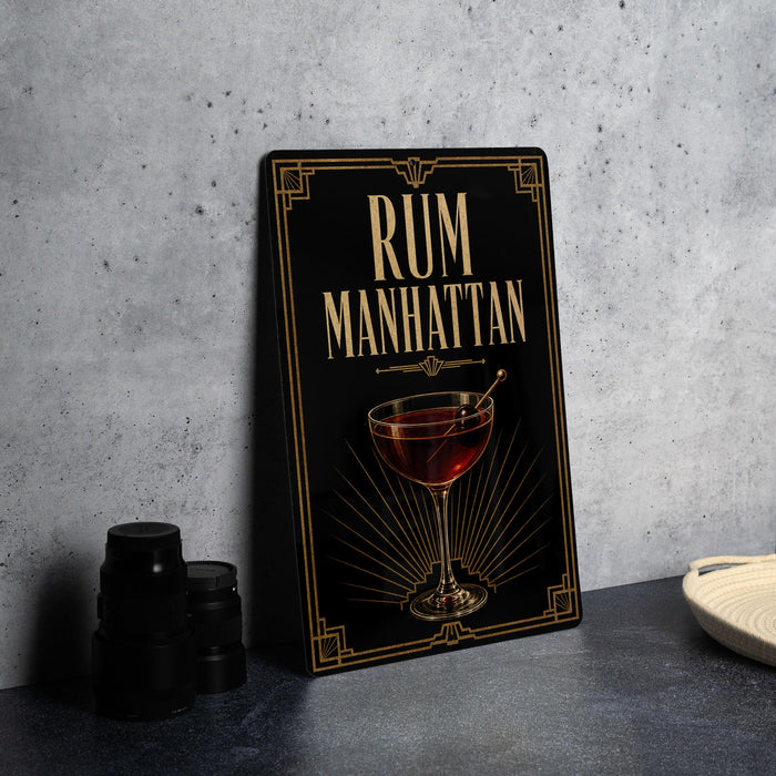 a framed poster with the title "RUM MANHATTAN" and an illustration of a glass containing a red drink.