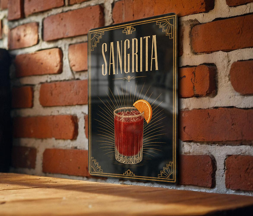 A framed poster of a Sangrita cocktail hangs on a brick wall, featuring an illustration of a glass filled with the drink and an orange slice.
