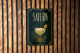 A poster with the word "SATURN" displayed prominently, featuring an illustration of a cocktail glass with a lemon twist.