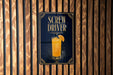 A sign for a Screw Driver cocktail is displayed on a wooden wall.