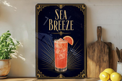 a framed advertisement for a Sea Breeze cocktail, with a glass of the drink and a slice of orange on the poster.