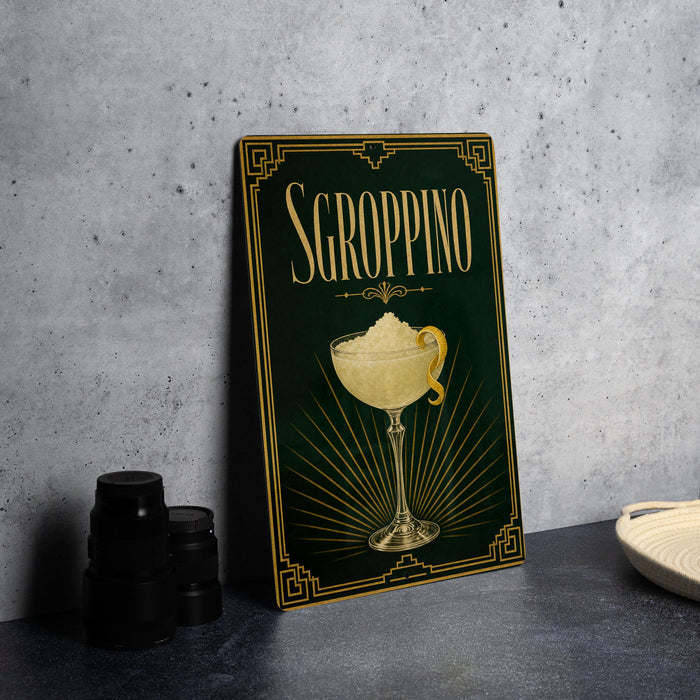 A framed poster of a cocktail called "SGROPPINO" is displayed on a gray wall, with a stack of black containers and a white dish visible to the side.