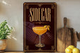 a decorative sign for a cocktail called "Sidegar" with a glass illustration and a lemon twist on a wooden surface.