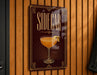 A sign for a cocktail called "Sidecar" is displayed on a wooden wall.