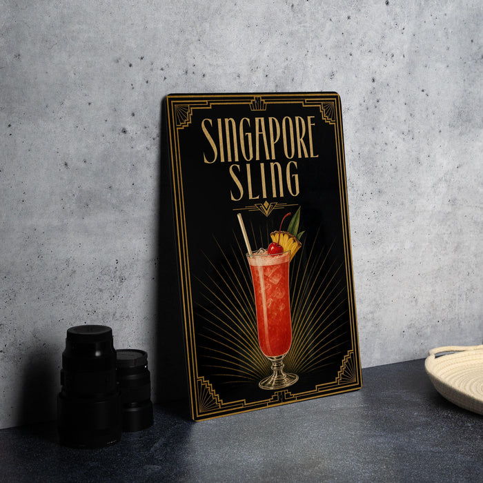 A framed poster of a Singapore Slinger cocktail is displayed on a wall, with a stack of black camera lenses and a white dish visible to the side.