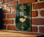 A sign with the text "SKULL AND BONES" and an illustration of a cocktail glass with a skull and crossbones symbol on it, mounted on a brick wall.