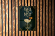 A poster with the title "SKULL AND BONES" displayed prominently, featuring an illustration of a cocktail glass with a skull and bones design.