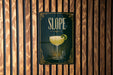 A sign for "Slope" cocktail is displayed on a wooden wall.
