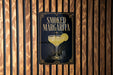 A sign for a "Smoked Margarita" cocktail is displayed on a wooden wall.