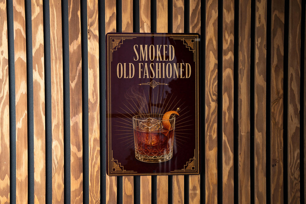 A sign that reads "SMOKED OLD FASHIONED" with an illustration of a glass of amber-colored liquid, possibly a cocktail, and garnish.