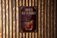A sign that reads "SMOKED OLD FASHIONED" with an illustration of a glass of amber-colored liquid, possibly a cocktail, and garnish.