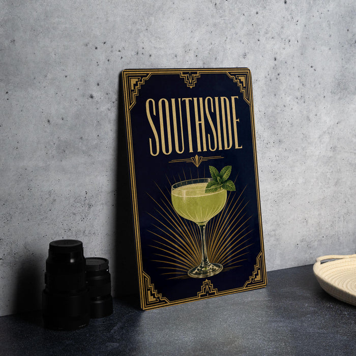 A decorative sign for a cocktail called "Southside" is displayed on a table, accompanied by a stack of black camera lenses and a white dish.