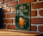A sign for "Spiked Apple Cider" is displayed on a brick wall, featuring an illustration of a glass of apple cider with a spiced apple slice.