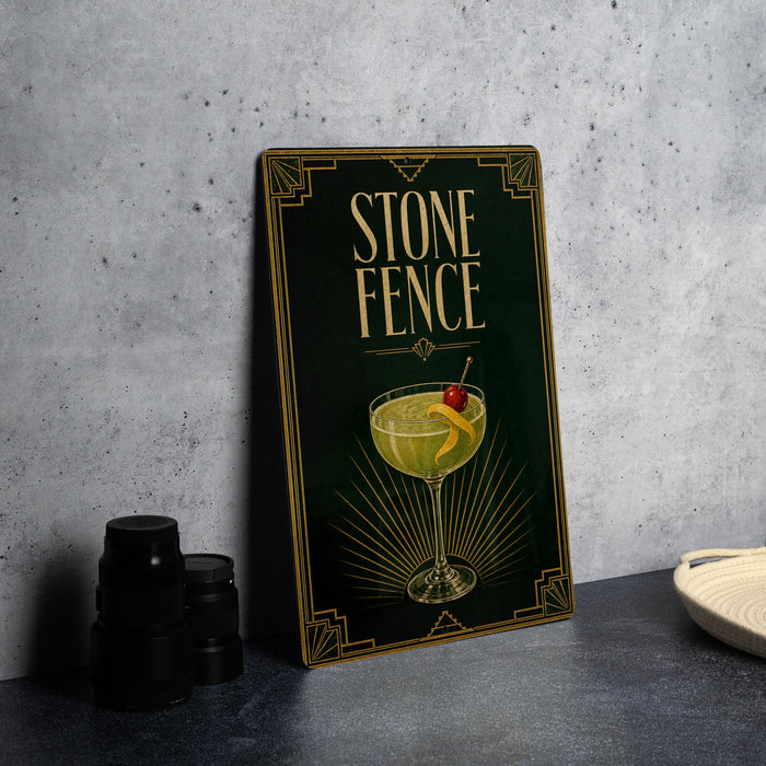 a framed poster with an illustration of a cocktail glass and a cherry on it, placed on a table next to some black camera lenses.