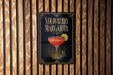 A sign for a strawberry margarita is displayed on a wooden wall.