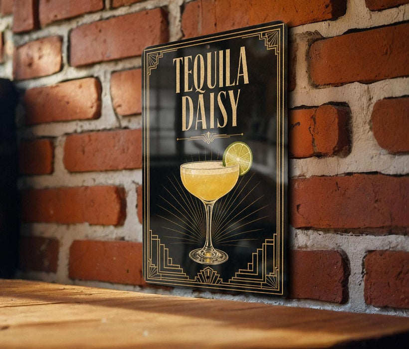A framed poster of a tequila daisy cocktail is displayed on a brick wall, with a wooden table below it.