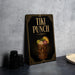 A framed poster or sign for "Tiki Punch" is displayed on a table, featuring an illustration of a tiki mug with tropical fruits and a tiki mask.