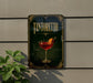 A framed poster of a Tintoretto cocktail is displayed on a wall, with a plant visible to the left.