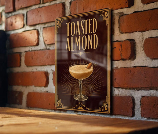 A sign with the text "Toasted Almond" and an illustration of a cocktail on a wooden surface against a brick wall background.
