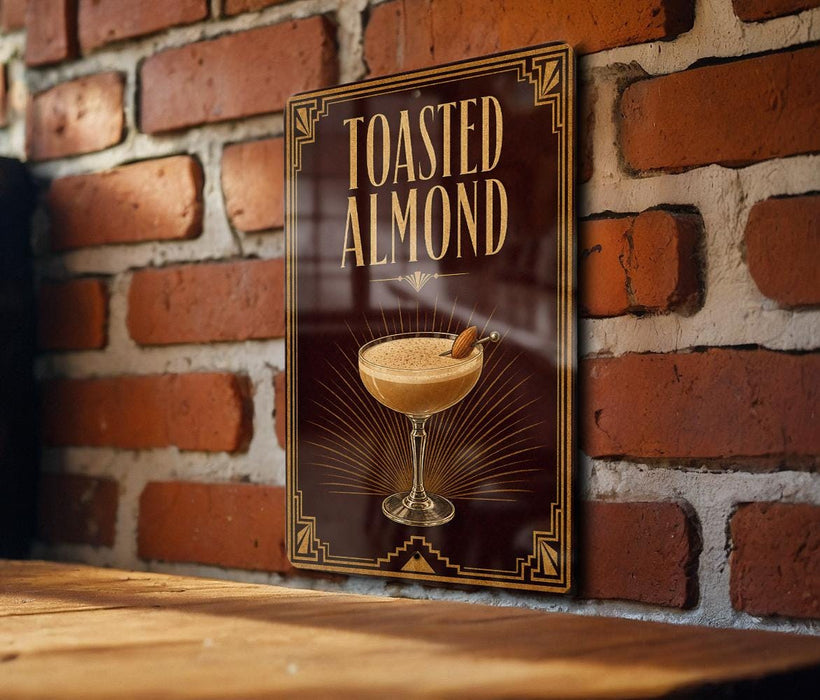A sign with the text "Toasted Almond" and an illustration of a cocktail on a wooden surface against a brick wall background.
