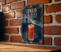 A sign for a tomato gin fizz cocktail is displayed on a brick wall.