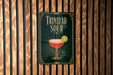 A sign for "Trinidad Sour" cocktail is displayed on a wooden wall.