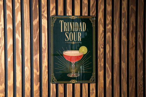 A sign for "Trinidad Sour" cocktail is displayed on a wooden wall.