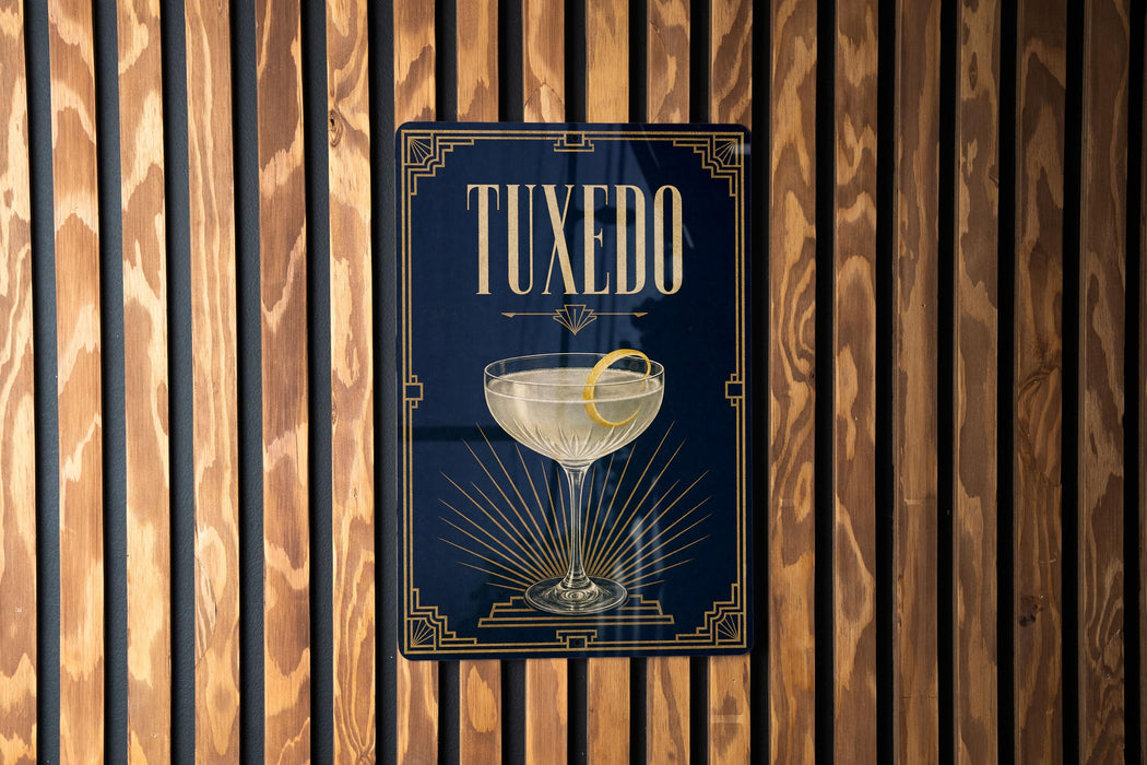 A framed poster with the word "Tuxedo" on it, featuring an illustration of a martini glass with a lemon twist.