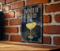 A sign with the text "TWENTIETH CENTURY" and an illustration of a cocktail glass on a brick wall.