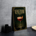 a framed poster of a Venetian cocktail, with a glass of the drink and a garnish on the poster.