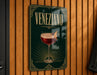 A sign with the word "Veneziano" on it, featuring an illustration of a glass of red wine with a cherry on top.