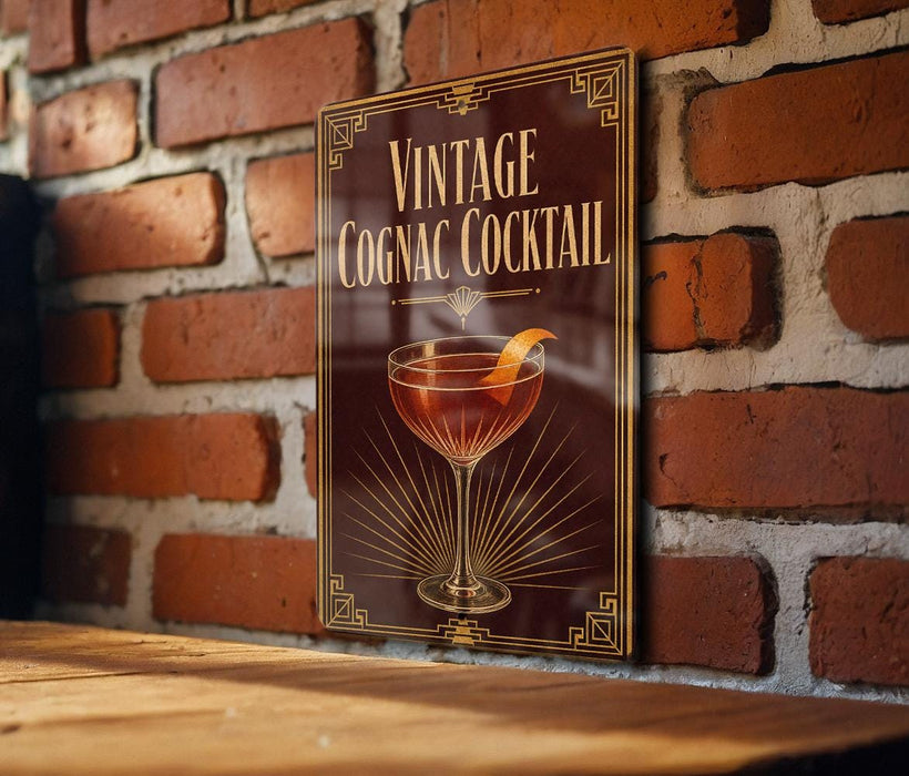 A vintage Cognac cocktail sign is displayed on a brick wall, featuring an illustration of a glass filled with the cognac drink and a slice of orange.
