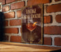 A vintage Cognac cocktail sign is displayed on a brick wall, featuring an illustration of a glass filled with the cognac drink and a slice of orange.