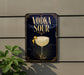 a sign with the text "VODKA SOUR" and an illustration of a cocktail glass with a lemon twist.
