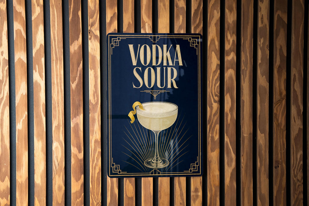 A sign with the text "VODKA SOUR" and an illustration of a cocktail glass with a lemon twist, mounted on a wooden wall.